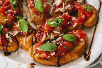 Tasty savory tomato Italian appetizers, or bruschetta, on slices of toasted baguette garnished with basil, close up on a Plate- Stock Photo or Stock Video of rcfotostock | RC-Photo-Stock