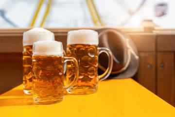 Three frothy beer mugs on a sunny  table in a beer tent with amusement rides in the background at oktoberfest or  dult in germany- Stock Photo or Stock Video of rcfotostock | RC Photo Stock