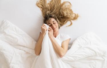 Top view of a satisfied young woman lying on a bed and cuddles with blanket at the bedroom- Stock Photo or Stock Video of rcfotostock | RC Photo Stock