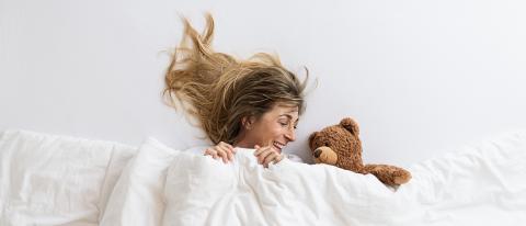 Top view of a woman that is surprise and looking to a teddy bear sleeping on white bed lying under blanket- Stock Photo or Stock Video of rcfotostock | RC Photo Stock