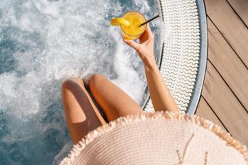 Top-down view of woman in whirlpool with drink, legs submerged, next to wooden deck- Stock Photo or Stock Video of rcfotostock | RC Photo Stock