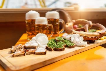 Traditional German beer mugs and food on a wooden tray in a beer tent with ferris wheel ride in the background at oktoberfest or  dult in germany- Stock Photo or Stock Video of rcfotostock | RC Photo Stock