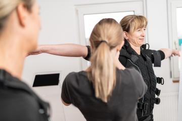 Trainer fitting an EMS training suit on a client in a EMS Studio environment.- Stock Photo or Stock Video of rcfotostock | RC Photo Stock