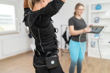 Trainer operating tablet to control EMS device on a client preparing for a workout
 : Stock Photo or Stock Video Download rcfotostock photos, images and assets rcfotostock | RC Photo Stock.: