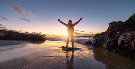 Traveler Woman with arms raised in triumph on a beach at sunset, silhouetted against vibrant sky and crashing waves. Travel and Freedom Concept image : Stock Photo or Stock Video Download rcfotostock photos, images and assets rcfotostock | RC Photo Stock.: