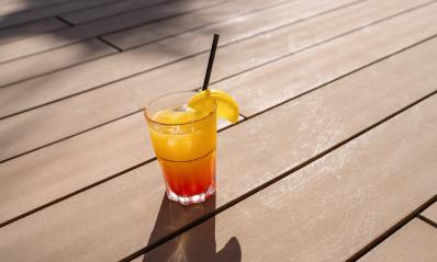 Tropical cocktail with orange slice on wooden deck, sunshine casting shadows, refreshing drink at a caribbean island hotel- Stock Photo or Stock Video of rcfotostock | RC Photo Stock