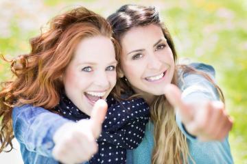 Two cheerful women outdoors smiling and giving thumbs up, radiating positivity and friendship, surrounded by a bright and colorful background of natural greenery and sunlight : Stock Photo or Stock Video Download rcfotostock photos, images and assets rcfotostock | RC Photo Stock.: