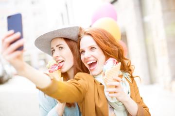 Two cheerful women with red hair enjoying colorful ice cream cones, taking a fun selfie in a bright urban setting with balloons in the background, capturing a joyful moment : Stock Photo or Stock Video Download rcfotostock photos, images and assets rcfotostock | RC Photo Stock.: