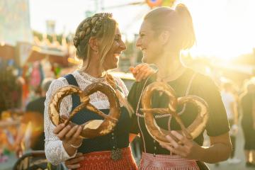 Two girlfriends together holding pretzel or brezen on a Bavarian fair or oktoberfest or duld in national costume or Dirndl in germany  : Stock Photo or Stock Video Download rcfotostock photos, images and assets rcfotostock | RC Photo Stock.: