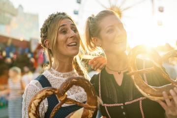 Two girlfriends together on a Bavarian fair or oktoberfest or duld in national costume or Dirndl with  pretzel or brezen : Stock Photo or Stock Video Download rcfotostock photos, images and assets rcfotostock | RC Photo Stock.: