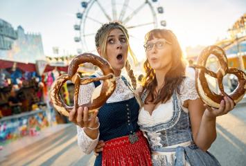 Two happy girlfriends together on a Bavarian fair or oktoberfest or duld in national costume or Dirndl with  pretzel or brezen in germany : Stock Photo or Stock Video Download rcfotostock photos, images and assets rcfotostock | RC Photo Stock.: