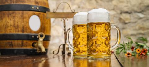 Two mugs of beer with foam and wooden barrel stand on the table, Oktoberfest, Munich, Germany- Stock Photo or Stock Video of rcfotostock | RC Photo Stock