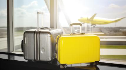 Two suitcases, one silver and one vibrant yellow, are positioned by an airport window. Outside, a matching yellow airplane is landing on the runway under a blue sky- Stock Photo or Stock Video of rcfotostock | RC Photo Stock