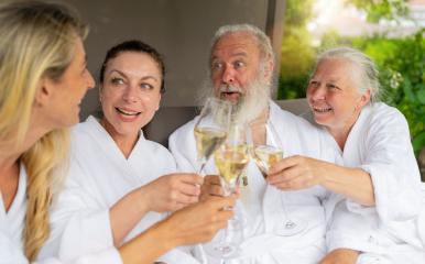 Two women and a senior couple laughing and toasting with champagne glasses at a spa wellnes hotel- Stock Photo or Stock Video of rcfotostock | RC Photo Stock