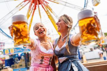 Two women in vibrant Bavarian dresses tracht joyfully toasting with large beer mugs at oktoberfest or duld in germany- Stock Photo or Stock Video of rcfotostock | RC Photo Stock