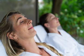 Two women relaxing on outdoor loungers, one in focus with eyes closed. Spa wellness hotel concept image- Stock Photo or Stock Video of rcfotostock | RC Photo Stock