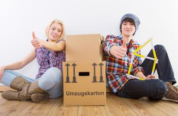 Two young people sitting on a wooden floor with moving boxes, smiling and giving thumbs up, with a measuring tool shaped like a house symbolizing a new home : Stock Photo or Stock Video Download rcfotostock photos, images and assets rcfotostock | RC Photo Stock.: