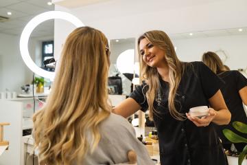 View from side of qualified makeup artist doing visage to young woman sitting at a high chair in beauty salon.  : Stock Photo or Stock Video Download rcfotostock photos, images and assets rcfotostock | RC Photo Stock.: