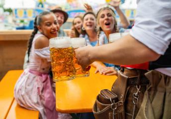 Waiter serving beer to a joyful group of friends at oktoberfest festival or duld in munich, amusement rides in the background- Stock Photo or Stock Video of rcfotostock | RC Photo Stock