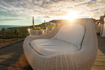 Wicker lounge chair on a hotel deck at sunset with ocean and mountain views- Stock Photo or Stock Video of rcfotostock | RC Photo Stock