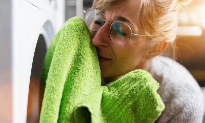 Woman at housework smells at fresh clothes from the clothes dryer- Stock Photo or Stock Video of rcfotostock | RC Photo Stock