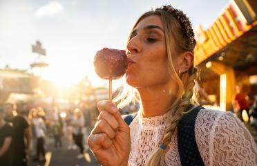 Woman eating candy apple at Oktoberfest wearing Dirndl in germany  : Stock Photo or Stock Video Download rcfotostock photos, images and assets rcfotostock | RC Photo Stock.: