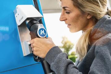 woman holds a fuel dispenser with hydrogen logo on gas station to fill up her car. h2 combustion engine for emission free eco friendly transport concept image- Stock Photo or Stock Video of rcfotostock | RC Photo Stock
