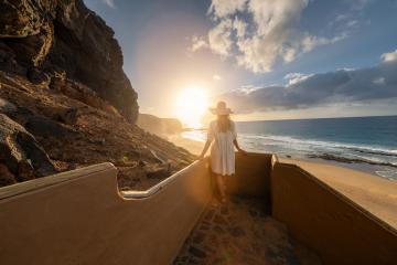 woman in a hat descending beach stairs at sunset, facing the ocean at Playa de Cofete, Fuerteventura, Canary Islands.- Stock Photo or Stock Video of rcfotostock | RC Photo Stock