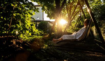 Woman in a white bathrobe relaxing on a wicker swing in the garden at spa wellness hotel : Stock Photo or Stock Video Download rcfotostock photos, images and assets rcfotostock | RC Photo Stock.: