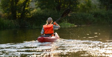 woman in an orange life vest paddles a red kayak on a sunlit river, viewed from behind with water droplets in air. Kayak Water Sports concept image- Stock Photo or Stock Video of rcfotostock | RC Photo Stock