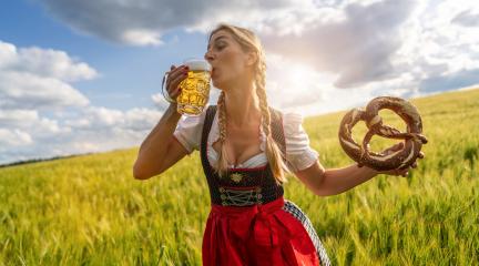 Woman in Bavarian tracht drinking beer and holding a big pretzel in a wheat field at sunset celebrating Oktoberfest festival in munich. : Stock Photo or Stock Video Download rcfotostock photos, images and assets rcfotostock | RC Photo Stock.: