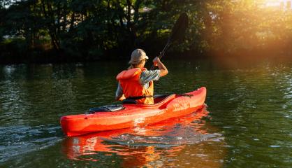 Woman in orange life vest kayaking on a tranquil river with lush greenery at sunset. Kayak Water Sports concept image- Stock Photo or Stock Video of rcfotostock | RC Photo Stock