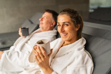 Woman in white robe holding a cup of tea smiling, man behind sipping his tea : Stock Photo or Stock Video Download rcfotostock photos, images and assets rcfotostock | RC Photo Stock.:
