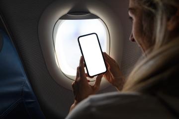 Woman on airplane holding mobile phone in hands with blank desktop screen by the window to take a photo Mockup image with copy space- Stock Photo or Stock Video of rcfotostock | RC Photo Stock