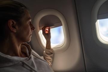 Woman on airplane looking out and a adjusting the sunshade the window on a airplane, sunlight streaming through- Stock Photo or Stock Video of rcfotostock | RC Photo Stock