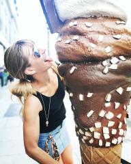 Woman playfully licking a large ice cream sculpture, wearing sunglasses, black top, denim skirt, and necklace, on a busy city street, bright and fun atmosphere
 : Stock Photo or Stock Video Download rcfotostock photos, images and assets rcfotostock | RC Photo Stock.: