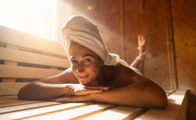 Woman relaxing in a finnish sauna, with a towel on her head, smiling at the camera- Stock Photo or Stock Video of rcfotostock | RC Photo Stock