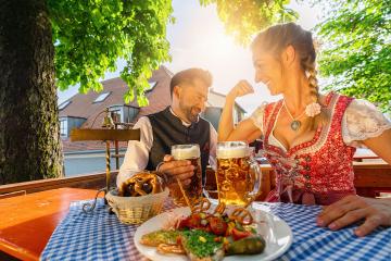 Woman showing strong muscles to his friend at the Beer garden or oktoberfest at summer and enjoy a glass of beer and the sun : Stock Photo or Stock Video Download rcfotostock photos, images and assets rcfotostock | RC Photo Stock.: