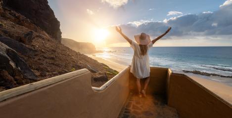Woman with arms outstretched at the beach stairs enjoying the sunset over the ocean at Playa de Cofete, Fuerteventura, Canary Islands.- Stock Photo or Stock Video of rcfotostock | RC Photo Stock