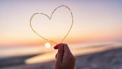 womand holding Heart shape made of led lights at the beach on sunset : Stock Photo or Stock Video Download rcfotostock photos, images and assets rcfotostock | RC-Photo-Stock.: