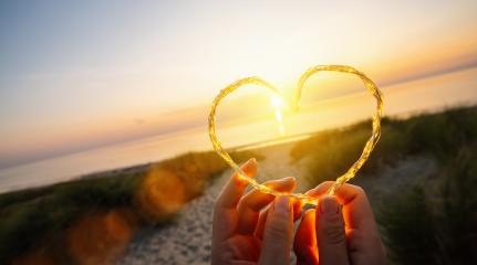 womand holding Heart shape made of led lights on the beach near the sea,  copyspace for your individual text.- Stock Photo or Stock Video of rcfotostock | RC-Photo-Stock