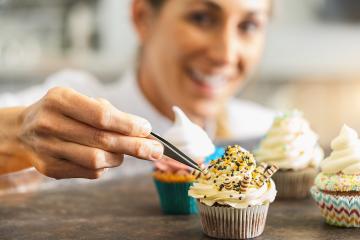 women in pastry bakery as confectioner draped chocolate candy topping on a colorful muffin  with tweezers : Stock Photo or Stock Video Download rcfotostock photos, images and assets rcfotostock | RC Photo Stock.: