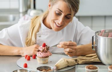 women in pastry bakery as confectioner draped pieces of chocolate on a muffin topping with tweezers : Stock Photo or Stock Video Download rcfotostock photos, images and assets rcfotostock | RC Photo Stock.: