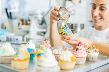 women in pastry bakery as confectioner sprinkles crumble mixture topping on a colorful muffin  by hand : Stock Photo or Stock Video Download rcfotostock photos, images and assets rcfotostock | RC Photo Stock.: