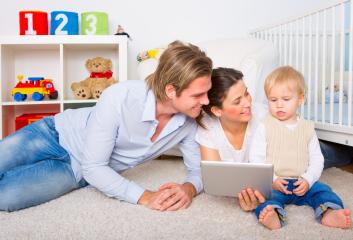 Young family with a toddler playing together on the floor, using a tablet in a bright and organized nursery with colorful toys, a teddy bear, and a crib in the background : Stock Photo or Stock Video Download rcfotostock photos, images and assets rcfotostock | RC Photo Stock.:
