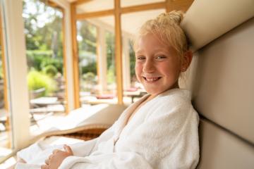 young girl relaxing in a lounger at a wellness spa hotel, smiling in a white robe, with a sunny garden view- Stock Photo or Stock Video of rcfotostock | RC Photo Stock