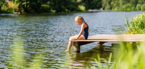 Young girl sitting alone on a wooden dock, dipping her feet in the lake on a sunny day at summer- Stock Photo or Stock Video of rcfotostock | RC Photo Stock