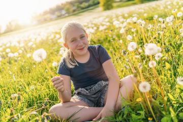 young girl sitting in a sunny field full of dandelions, holding one in her hand and smiling joyfully. The sun is shining brightly, capturing the essence of a warm and vibrant spring day. : Stock Photo or Stock Video Download rcfotostock photos, images and assets rcfotostock | RC Photo Stock.: