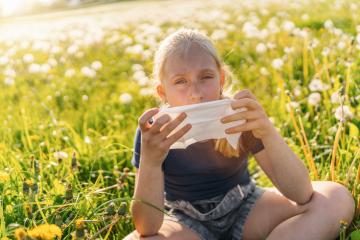 young girl sitting in a sunny field full of dandelions, holding a handkerchief to her face, showing signs of allergy to pollen and grasses in spring. The sun is shining brightly at a warm spring day : Stock Photo or Stock Video Download rcfotostock photos, images and assets rcfotostock | RC Photo Stock.: