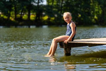 Young girl sitting on a wooden dock, smiling and dangling her feet in the lake on a sunny day in germany : Stock Photo or Stock Video Download rcfotostock photos, images and assets rcfotostock | RC Photo Stock.: